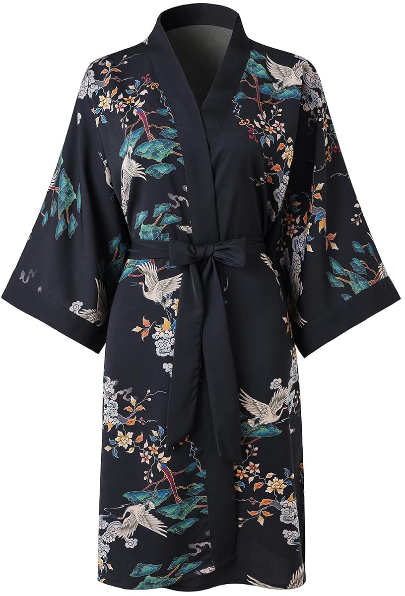 Peignoir kimono noir à motif floral, ceinture nouée et poches, posé dans une chambre au linge crème.