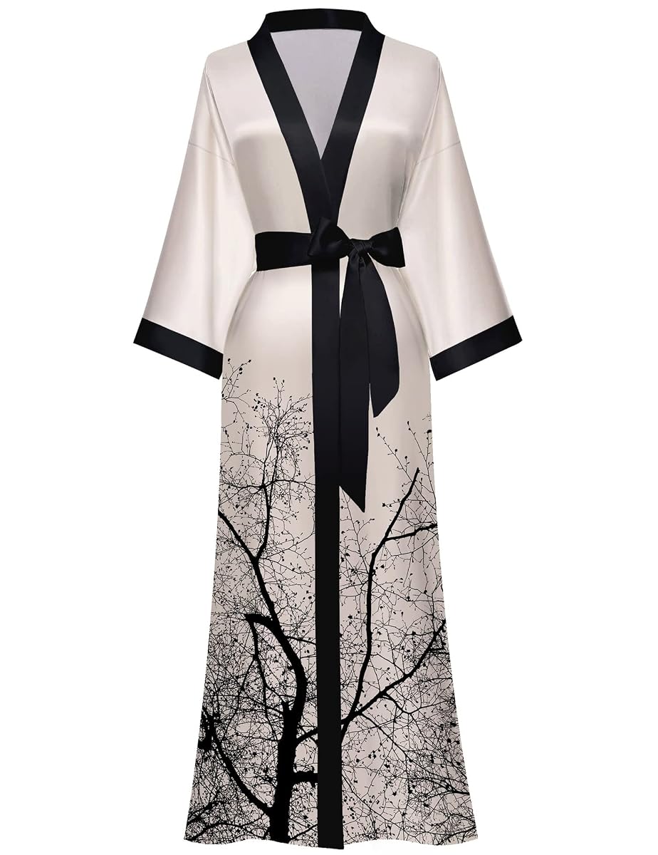 Kimono long en satin à motif floral sombre, suspendu dans une chambre lumineuse au linge froissé.